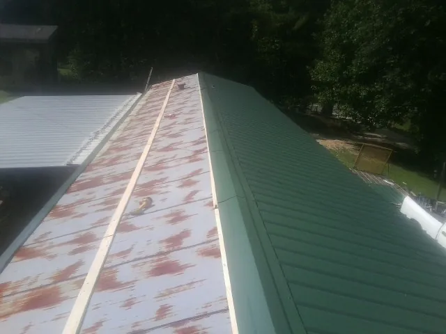 Old rusted panels beside newly installed green metal roofing — Wind Damage Roof Repair by Roofing Brothers in Grand Prairie