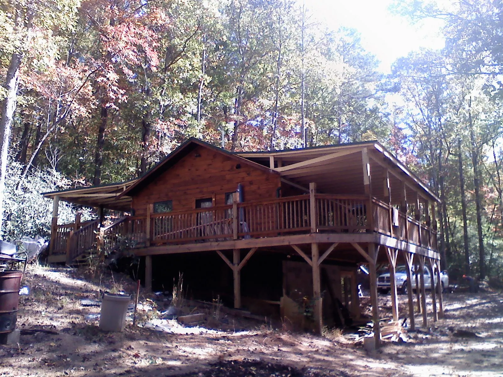 Log cabin with a wraparound porch and metal roof in the fall in Grand Prairie