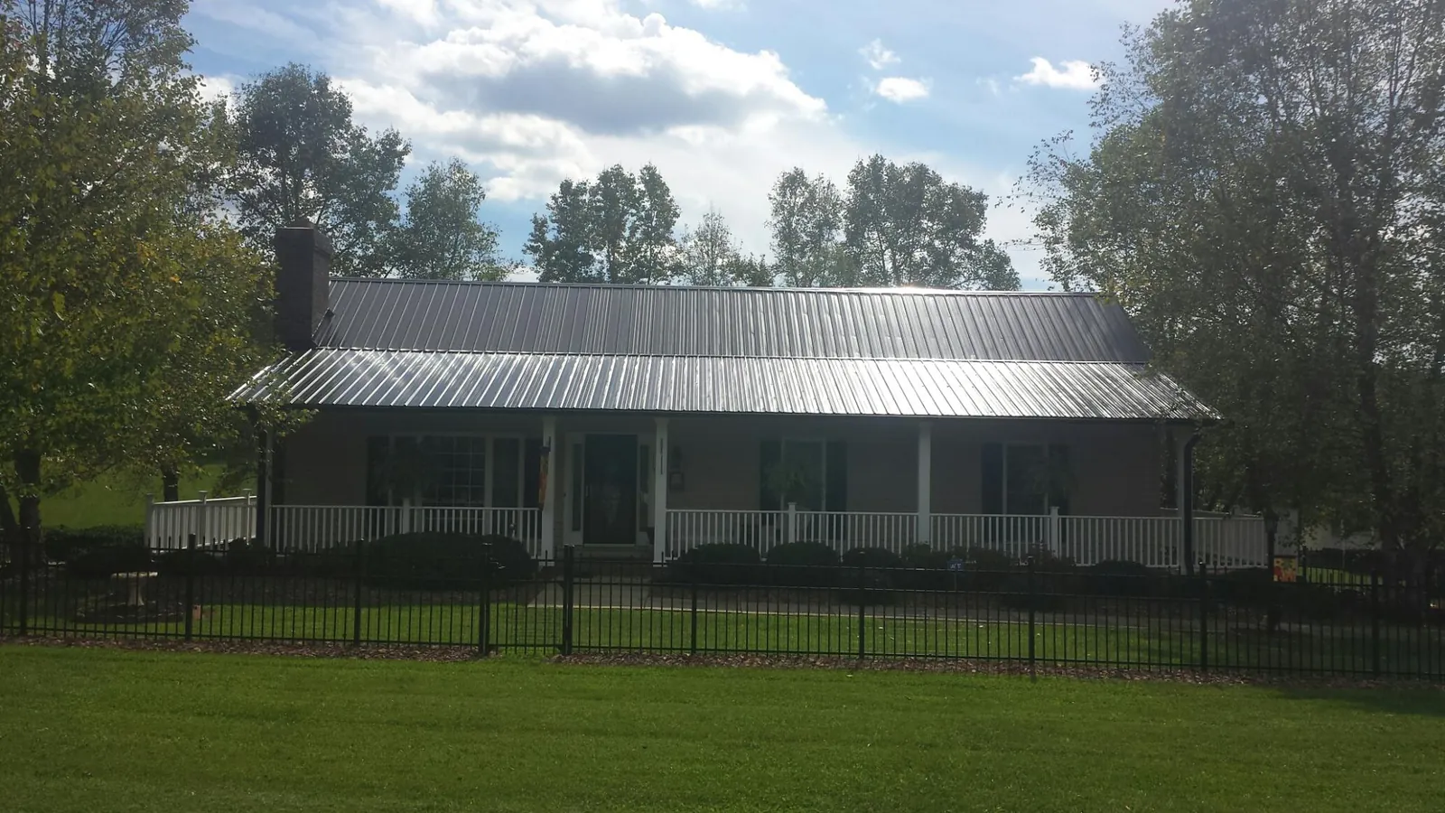 Gray metal roof on a brick ranch with a full width front porch — Gutter Guard Installation work by our crew in Grand Prairie