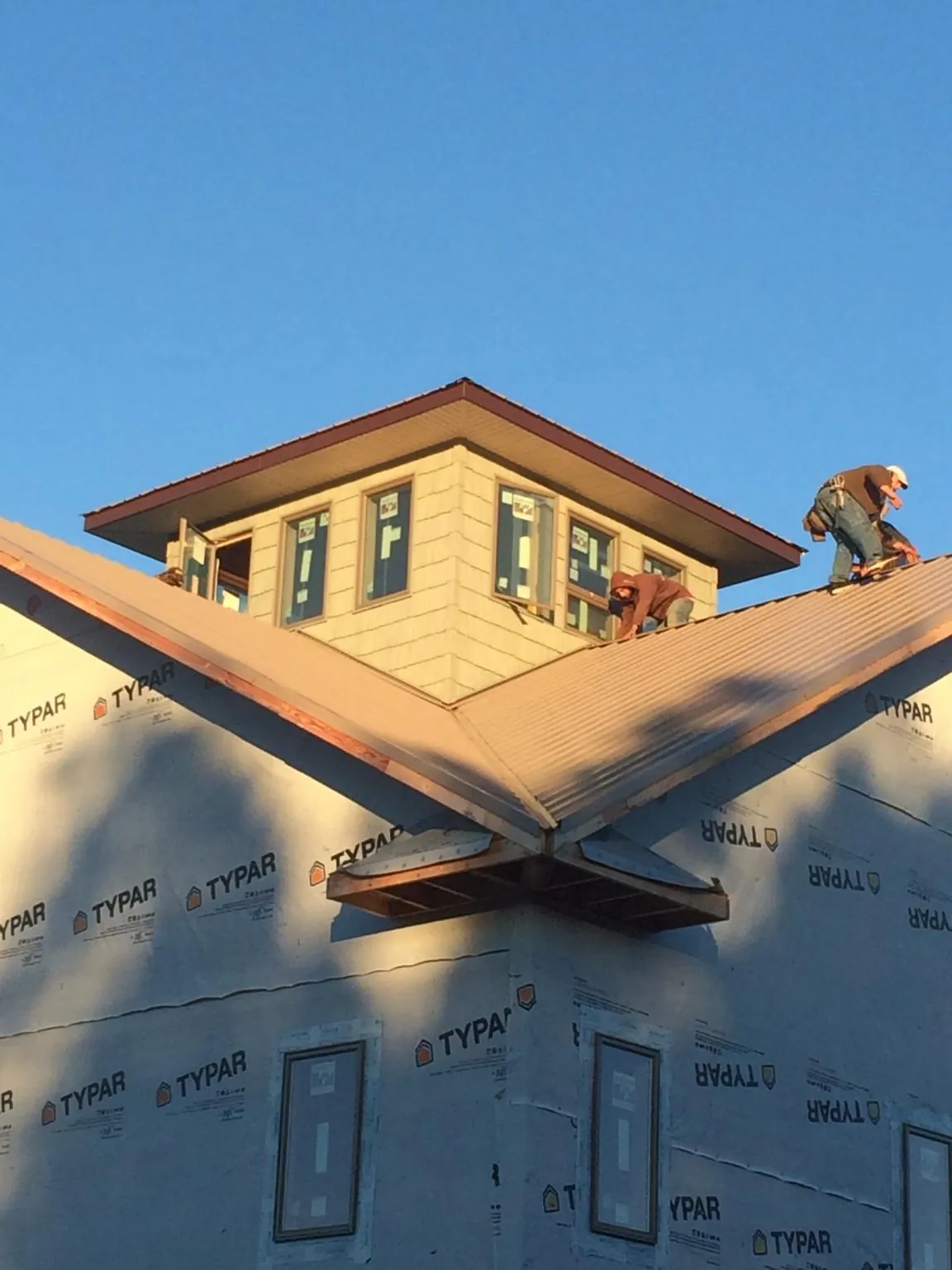 Roofers working around a rooftop cupola on a new metal roof at sunset — Roof Waterproofing in Grand Prairie by Roofing Brothers